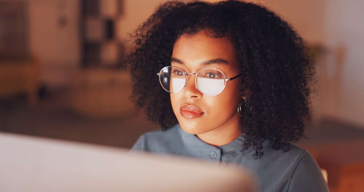 Person reading online with a reflection of the screen on their glasses