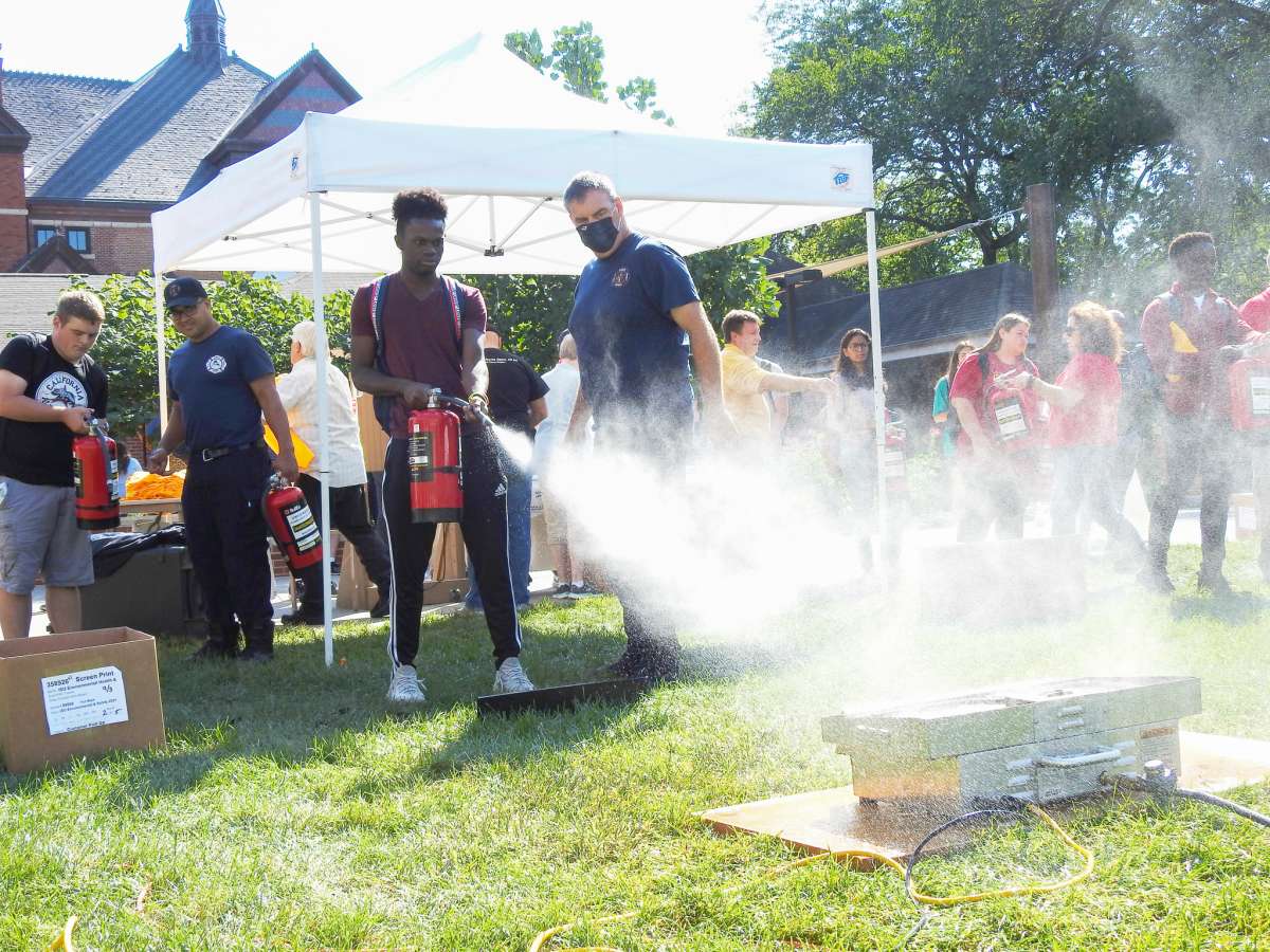 Student extinguishes a simulated fire on campus