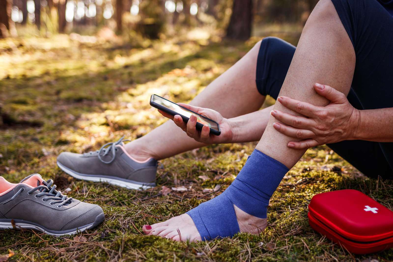 Person with bandaged ankle uses a mobile phone